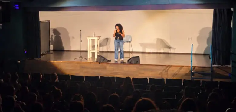 סטנדאפיסטית על הבמה מול אולם מלא, מופע סטנדאפ באנגלית עם שחר הלוי, 2026